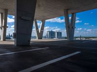 a parking garage with concrete columns and some sky in the background of this photo there are clouds