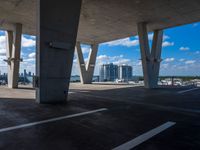 a parking garage with concrete columns and some sky in the background of this photo there are clouds