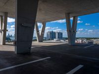 a parking garage with concrete columns and some sky in the background of this photo there are clouds