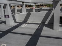 empty parking garage space with shadows cast on it's walls and flooring in the area