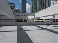 an empty concrete parking garage in front of high rise buildings and skyscrapers in a sunny day