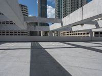 an empty concrete parking garage in front of high rise buildings and skyscrapers in a sunny day