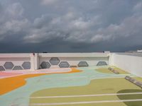 the colorful painted roof of a parking lot in a city is dark gray clouds in the sky above