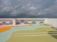 the colorful painted roof of a parking lot in a city is dark gray clouds in the sky above