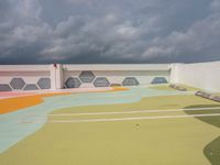 the colorful painted roof of a parking lot in a city is dark gray clouds in the sky above