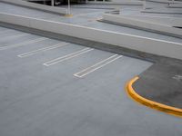 a parking lot with several yellow lines on the floor and a few parked cars in the parking garage