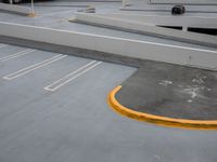 a parking lot with several yellow lines on the floor and a few parked cars in the parking garage