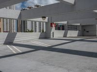 an empty parking lot with no one standing next to the curb and buildings in the background