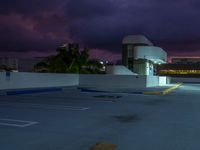 the parking lot is empty at dusk with a cloudy sky in the background and two cars parked along the curb