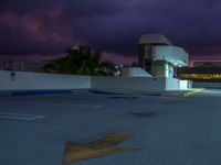 the parking lot is empty at dusk with a cloudy sky in the background and two cars parked along the curb