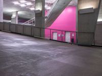 an indoor parking lot with stairs, and railings in pink and gray colors on the walls