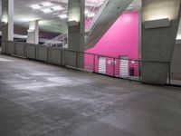 an indoor parking lot with stairs, and railings in pink and gray colors on the walls