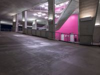 an indoor parking lot with stairs, and railings in pink and gray colors on the walls