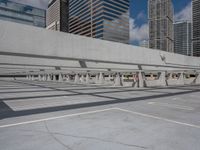 an empty parking lot surrounded by tall buildings and tall glass skyscrapers in the background