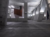 a parking garage is lined with cement columns and a skateboard on the sidewalk near by