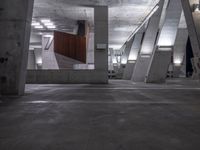 a parking garage is lined with cement columns and a skateboard on the sidewalk near by