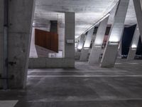 a parking garage is lined with cement columns and a skateboard on the sidewalk near by