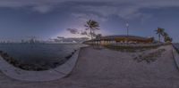 a panoramic view of a river with trees and buildings at dusk at the shore