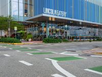 an outside city mall with green and white lines, a large glass front building, and some trees