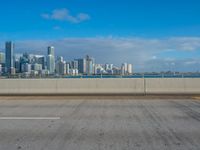 a long stretch of road next to the water and the city skyline with many buildings