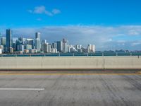 a long stretch of road next to the water and the city skyline with many buildings