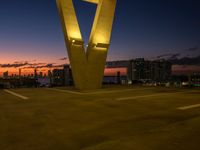 the large letter v stands on top of a parking lot at dusk with a dark sky in the background