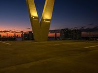 the large letter v stands on top of a parking lot at dusk with a dark sky in the background