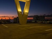 the large letter v stands on top of a parking lot at dusk with a dark sky in the background