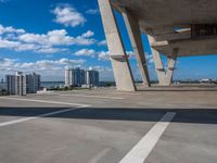 a skate board in a parking lot in front of tall buildings with a sky background