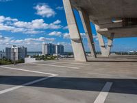 a skate board in a parking lot in front of tall buildings with a sky background