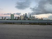 a city skyline next to a wide river on the street and bench with benches overlooking it