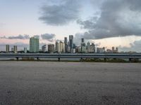 a city skyline next to a wide river on the street and bench with benches overlooking it