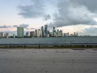 a city skyline next to a wide river on the street and bench with benches overlooking it