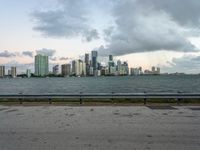 a city skyline next to a wide river on the street and bench with benches overlooking it