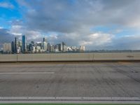 the city skyline is visible in a dark cloudy day, from a bridge in front