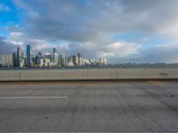 the city skyline is visible in a dark cloudy day, from a bridge in front