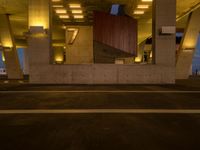 a parking garage filled with lots of cement pillars and windows at dusk with neon lights