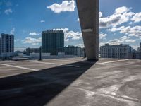 an open air parking lot and skyline view in front of buildings and sky high rise condo buildings