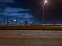 the road is empty during the nighttime time scene with a view of a city skyline