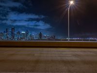 the road is empty during the nighttime time scene with a view of a city skyline