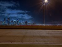 the road is empty during the nighttime time scene with a view of a city skyline