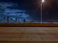 the road is empty during the nighttime time scene with a view of a city skyline