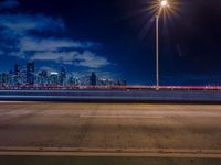 the road is empty during the nighttime time scene with a view of a city skyline