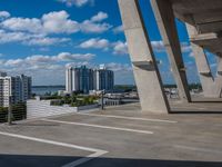 large bridge stretching over parking lot next to high rise buildings on river shore in residential area