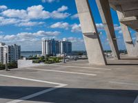 large bridge stretching over parking lot next to high rise buildings on river shore in residential area