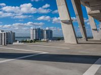 large bridge stretching over parking lot next to high rise buildings on river shore in residential area