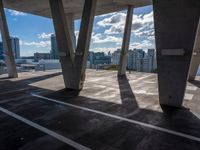 a lot of pillars that look like concrete with sky and city in the background under it