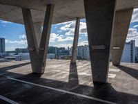 a lot of pillars that look like concrete with sky and city in the background under it