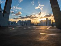 a sunny sky at dusk with the sun setting over skyscrapers and parking spaces behind it