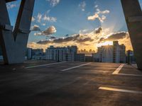 a sunny sky at dusk with the sun setting over skyscrapers and parking spaces behind it